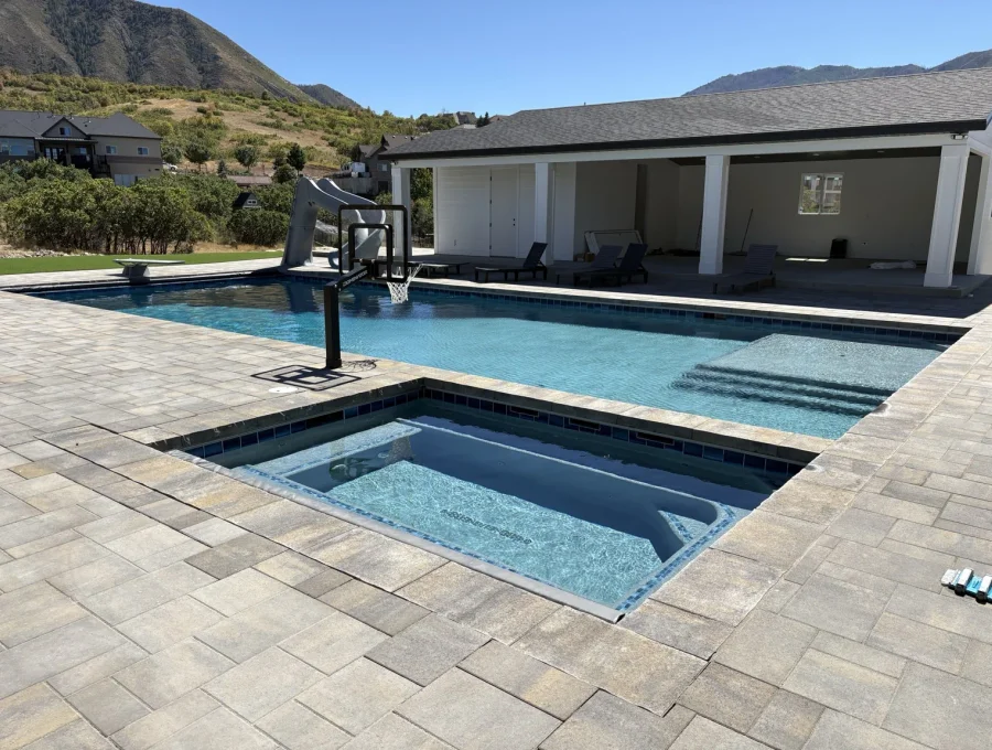 Flush-mounted spa set into the pool deck with stone coping