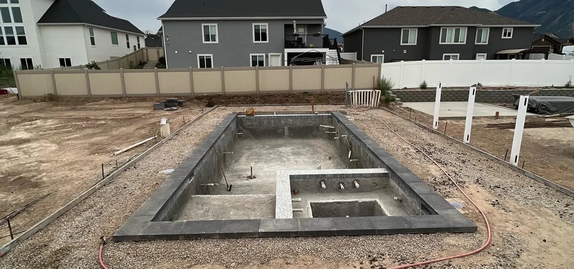 Crew applying shotcrete over a rebar grid in an excavated pool shell at a Utah County home